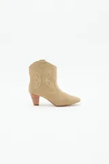 Bota corta de cuero gamuzado color beige, estilo texana, con taco medio de 6 cm y diseño de mariposa en los laterales.