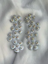 Aros colgantes con forma de flores de acrílico color blanco y centro con strass.