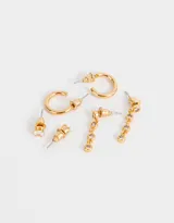 Set de tres pares de aros dorados bañados en oro con circonitas cúbicas. Incluye un par de aros tipo solitario, un par de aros colgantes con tres circonitas y un par de aros tipo argolla.