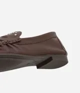 Mocasín de cuero color marrón con puntera fina, detalle de pliegues y tachuelas plateadas.