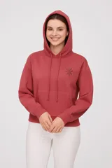 Buzo color ladrillo con capucha, cordones ajustables, bolsillo tipo canguro y puños y ruedo acanalados. Estampado de flor en el pecho.