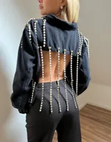 Campera cropped de jean negra con tiras de strass plateado y botones plateados al frente.