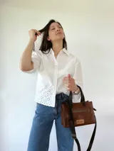 Cartera bandolera de cuero color marrón tostado, con doble asa corta y correa larga desmontable. Tiene un bolsillo frontal con cierre y un bolsillo interno.