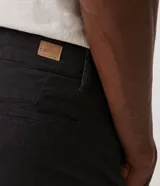 Pantalón masculino de sarga color beige, corte slim, con cierre de botón y cremallera, trabillas en la cintura y bolsillos delanteros y traseros.
