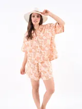 Short de tela color salmón con estampado de motivos marinos en blanco y marrón, cintura elastizada con cordón ajustable.