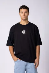 Remera oversize blanca de algodón con un pequeño estampado circular en el pecho que simula un cerebro o un diseño abstracto en espiral, en color negro.