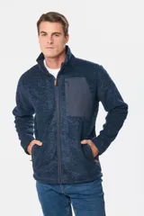 Campera de abrigo azul de corderito con interior de polar y cierre frontal. Presenta un bolsillo de tela lisa en el pecho y bolsillos laterales con cierre.