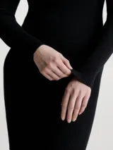 Vestido de punto negro con cuello alto y manga larga, confeccionado en 100% lyocell, con diseño slim y textura canalé.