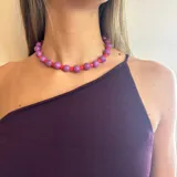 Collar corto de cuentas redondas grandes color violeta alternadas con cuentas tubulares pequeñas color rojo.