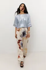 Blusa de lino color beige con brillo sutil, corte holgado, mangas cortas y cuello redondo.