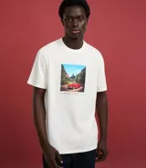 Remera de algodón color crema con cuello redondo y mangas cortas. Presenta un estampado rectangular con la imagen de un auto rojo en un paisaje y texto en la parte inferior.