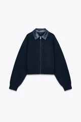 Chaqueta bomber azul marino de tejido de punto con cuello solapa de cuero sintético a contraste y manga larga. Cierre frontal con cremallera metálica.