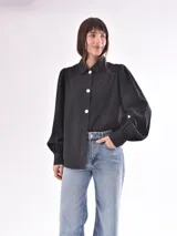 Camisa verde oliva con rayas verticales en relieve, corte clásico, cuello camisero, cierre frontal con botones blancos, mangas largas abullonadas con puños elastizados.