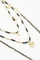 Collar de tres vueltas con cuentas doradas y negras, y dijes circulares dorados.