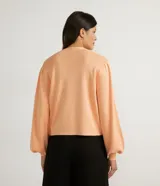 Chaqueta corta de punto color negro, con escote en V, manga larga abullonada, sisa desplazada, abotonado frontal total con botones forrados y puños acanalados.