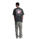 Remera de algodón color gris oscuro con efecto lavado, corte oversize y cuello redondo. Presenta un pequeño estampado circular en el pecho izquierdo con texto en rosa y un diseño gráfico central.