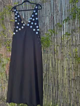 Vestido largo negro con escote en V profundo, tirantes finos y apliques circulares metálicos plateados en el área del busto.