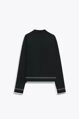 Chaqueta corta negra de punto con cuello solapa, manga larga y cierre frontal con botones.