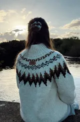 Sweater tejido a mano en lana merino color crema con diseño geométrico en marrón y beige en el cuello, pecho y puños.