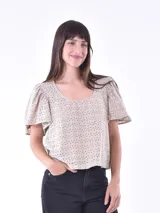 Blusa color blanco con mangas cortas abullonadas y calado con pequeños orificios.