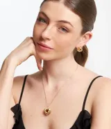 Conjunto de collar y aros dorados con colgante y dije en forma de nudo.