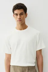 Remera blanca de punto texturizado de peso medio, corte estándar, cuello redondo y mangas cortas.