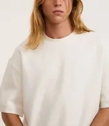 Remera color crema de corte amplio, con cuello redondo y mangas cortas con sisa desplazada. Confeccionada en algodón y poliéster.