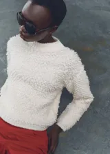 Sweater de punto grueso color blanco con terminaciones de canalé, cuello redondo y tejido bouclé.