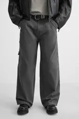 Pantalón gris oscuro de corte amplio, con bolsillos frontales y traseros de parche. Incluye un bolsillo lateral con cierre de cremallera.