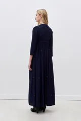 Vestido largo azul marino con bordados dorados en el frente, mangas largas y falda acampanada.