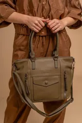 Cartera bandolera de símil cuero color marrón claro, con doble asa rígida y correa regulable. Presenta dos bolsillos frontales con cierre vertical y un bolsillo frontal con solapa y botón. Cuenta con dos divisiones internas.