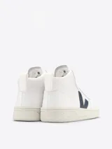 Championes de caña alta Veja V-15, color blanco con logo lateral en azul marino. Fabricados en cuero con forro de poliéster reciclado y suela de caucho del Amazonas.