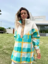 Buzo largo con cuello alto de polar color crema y cuerpo con estampado de cuadros en tonos celeste, amarillo y blanco.