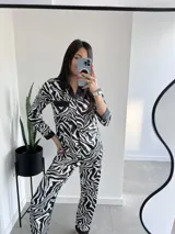 Conjunto de pijama de dos piezas con estampado de cebra en blanco y negro. Incluye una camisa de manga larga con botones y un pantalón largo de corte recto.