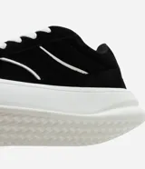 Championes negros de estilo skater con cordones gruesos blancos, suela blanca y detalles de líneas curvas blancas en los laterales.