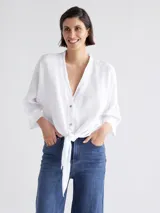 Camisa blanca con lazo frontal y botones, de manga larga y corte holgado.