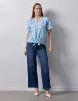 Blusa de algodón estampado a rayas verticales en tonos celeste, azul y verde. Tiene cuello a la base, escote en V con bordado y botones. Terminación de ruedo con nudo.