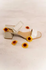 Sandalia de cuero color beige con tiras anchas y ajuste de velcro. Tiene taco cuadrado de 4,5 cm y plantilla de cuero.
