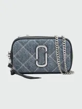 Bandolera Marc Jacobs modelo The Quilted Denim Softshot, confeccionada en denim azul acolchado con patrón de rombos. Presenta el logo Double J en metal plateado, correa de cuero y cadena, y cierre de cremallera doble.