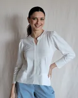 Remera blanca de manga larga con cuello en V y detalle de costuras verticales en el frente.