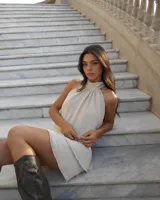 Vestido corto color beige, con cuello halter y espalda descubierta.