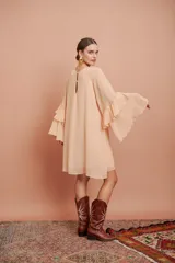 Vestido corto color salmón claro, de mangas largas con volados y corte suelto.