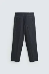Pantalón de denim azul oscuro, corte wide fit, largo cropped, con pliegues frontales, bolsillos laterales y traseros asimétricos. Cierre frontal con cremallera y gancho metálico oculto.