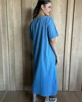 Vestido midi negro con cuello redondo y mangas cortas. Presenta dos bolsillos cuadrados en el pecho y ribetes blancos en cuello, mangas, bolsillos y ruedo.