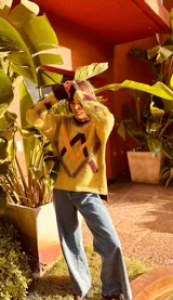 Sweater de punto color pistacho y marrón chocolate, con cuello alto y diseño geométrico bordado en el frente.