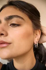 Aros de acero quirúrgico hipoalergénico con forma de argolla plateada y dije circular colgante de piedra natural color azul.