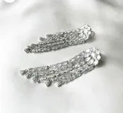 Aros largos plateados con forma de lágrima, con incrustaciones de zirconia y diseño de flecos.