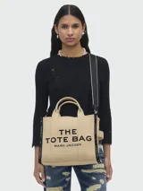 Bolso tote de tela color beige con estampado del logo de la marca en negro. Tiene doble asa de mano y correa de hombro extraíble y ajustable en color negro.