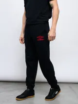 Pantalón de jogging negro de felpa con puños, cordón ajustable en la cintura y logo de Umbro bordado en rojo en la pierna izquierda.