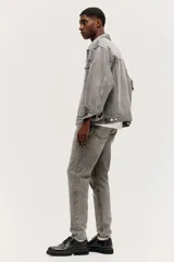 Pantalón de jean gris con efecto lavado, corte regular tapered, tiro medio, cinco bolsillos y cierre con botón y cremallera.